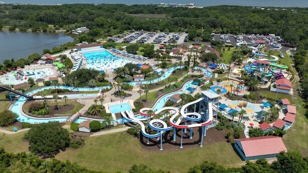 An aerial view of a water park with multiple slides and pools, surrounded by parking and greenery. - The Salty Tortoise - By Beach (Jekyll Island)