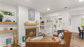 A modern living room with a fireplace, wooden shelves, and comfortable seating. - The Salty Tortoise - By Beach (Jekyll Island)
