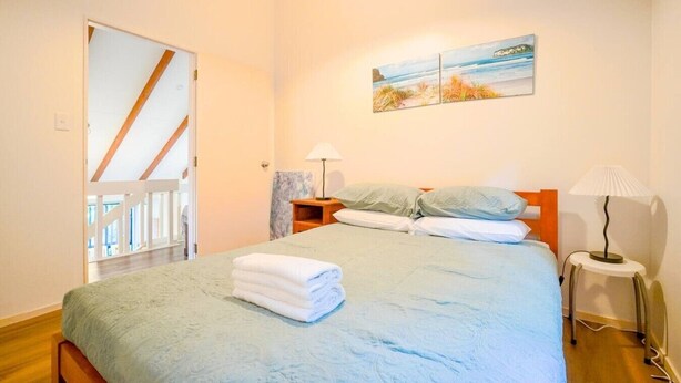 Un dormitorio con una cama, dos lámparas de noche, un cuadro y vistas a un balcón.