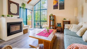 Amplia sala de estar con chimenea, un ventanal grande, un sofá y una mesa de centro.