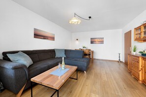 Een moderne woonkamer met een bank, salontafel en houten kast.