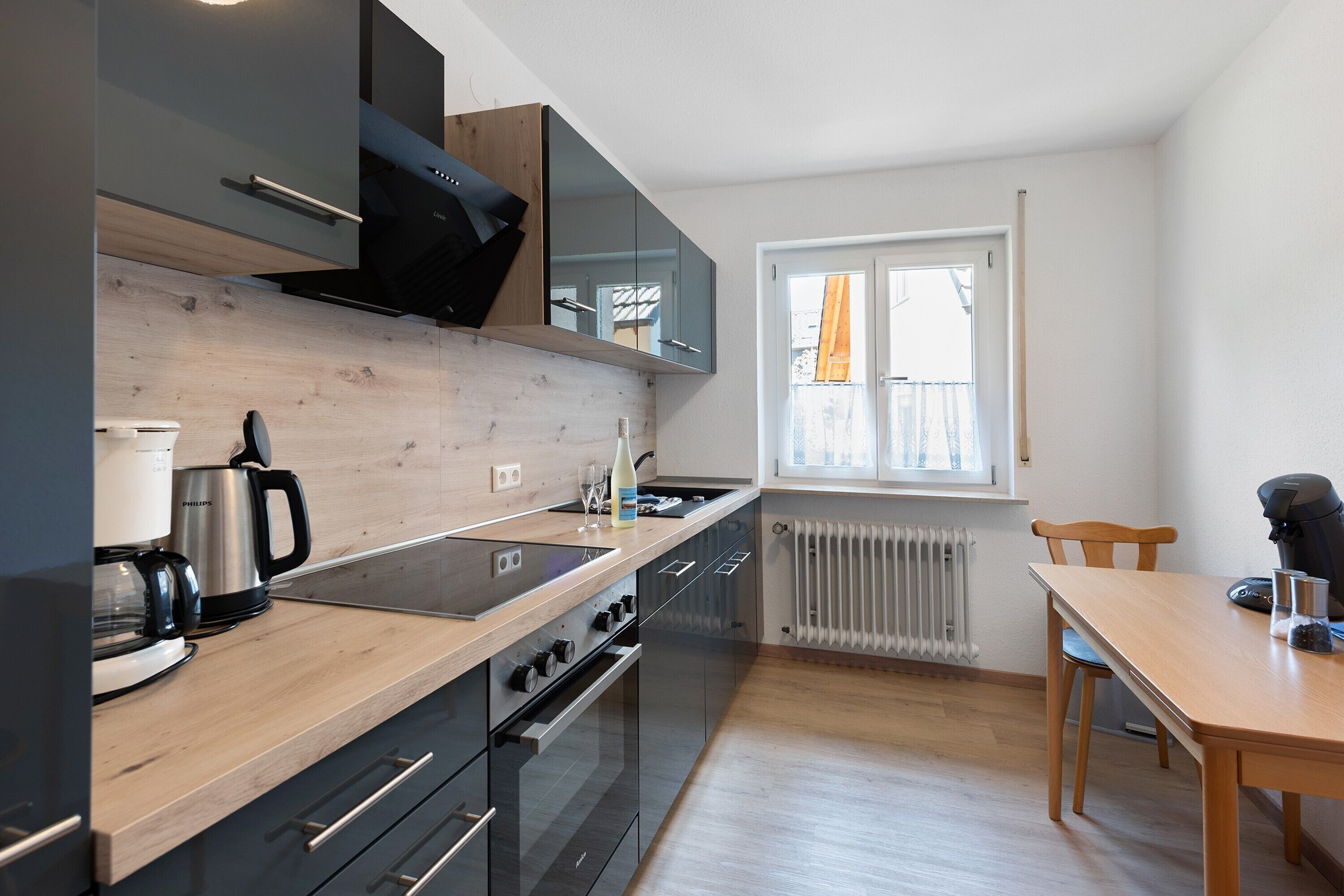 Eine moderne Küche mit Holzarbeitsplatte, schwarzen Schränken, einem eingebauten Ofen und einem Fenster mit Blick.