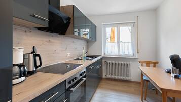 Eine moderne Küche mit Holzarbeitsplatte, schwarzen Schränken, einem eingebauten Ofen und einem Fenster mit Blick.