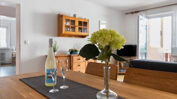 Ein Esstisch mit einer Flasche, zwei Gläsern und einer Blumenvase.