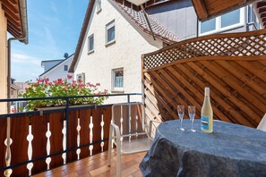 Ein Balkon mit Tisch, zwei Gläsern und einer Flasche Weißwein.