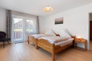 Een slaapkamer met een houten bed, een nachtkastje met een lamp, een stoel en een raam met dunne gordijnen.