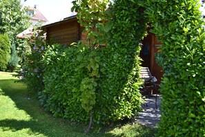 A wooden cabin with a covered patio area, surrounded by dense greenery and a well-maintained lawn. - Apartment '2' with Lake View, Private Garden and Wi-Fi (Hagnau am Bodensee)