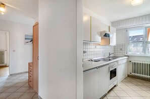 A kitchen with white cabinets, a stove, and a window.