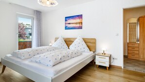 A bedroom with a bed, bedside table, and a view of the outdoors. - Apartment '3' with Private Garden, Balcony and Wi-Fi (Hagnau am Bodensee)