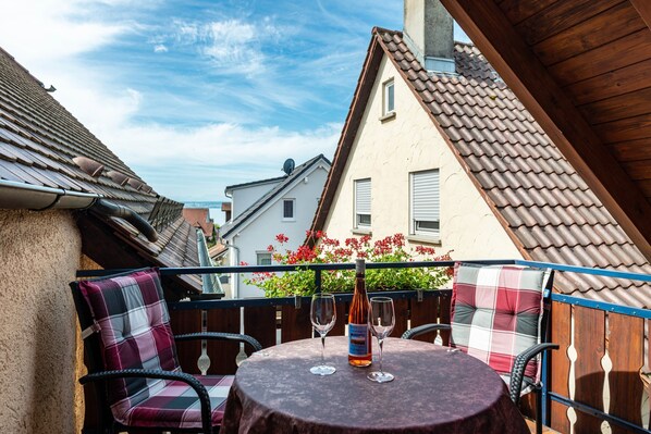 A balcony with a round table, two chairs, and two wine glasses.