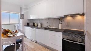 Una cocina moderna con armarios blancos, horno empotrado y fregadero.