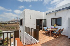 Un patio con mesa y sillas, baranda y vista del paisaje.
