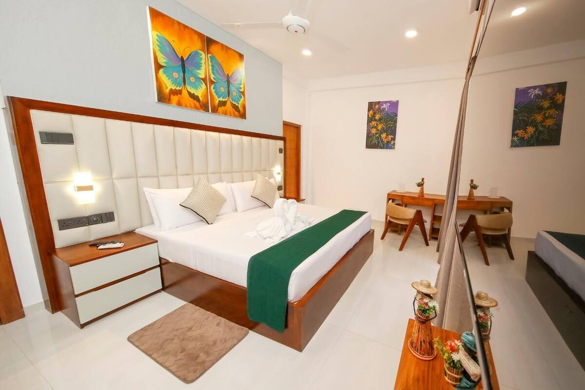A modern hotel room with a large bed, a desk, and a dining area.
