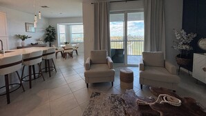 A spacious living area with a dining table, two sofas, and a coffee table. There is a balcony with a view of the outdoors. - WELLEN GOLF & COUNTRY CLUB GATAWAY 
In a Modern Style 2 bd Condo (Venice)