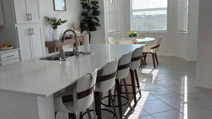 A modern kitchen with a large island, white cabinetry, and bar stools. - WELLEN GOLF & COUNTRY CLUB GATAWAY 
In a Modern Style 2 bd Condo (Venice)