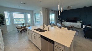 A modern kitchen with a central island, stainless steel appliances, and pendant lighting. - WELLEN GOLF & COUNTRY CLUB GATAWAY 
In a Modern Style 2 bd Condo (Venice)