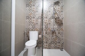 A bathroom with a shower, toilet, and patterned tiles.