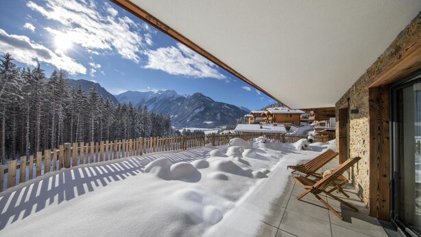 A balcony with a view of snow-covered mountains and trees. - Chalet in Neukirchen by the Slopes (Neukirchen am Grossvenediger)