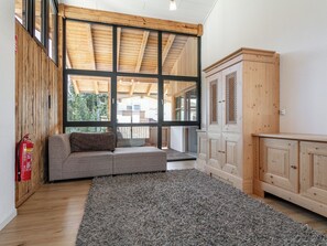 Relax in this spacious room with a high ceiling, large windows, and a comfortable sofa.