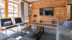 Moderni olohuone, jossa on puuseinä, litteänäyttöinen televisio ja sohva.