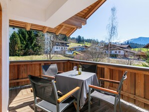 Enjoy a serene mountain view from this deck with a table and two chairs.