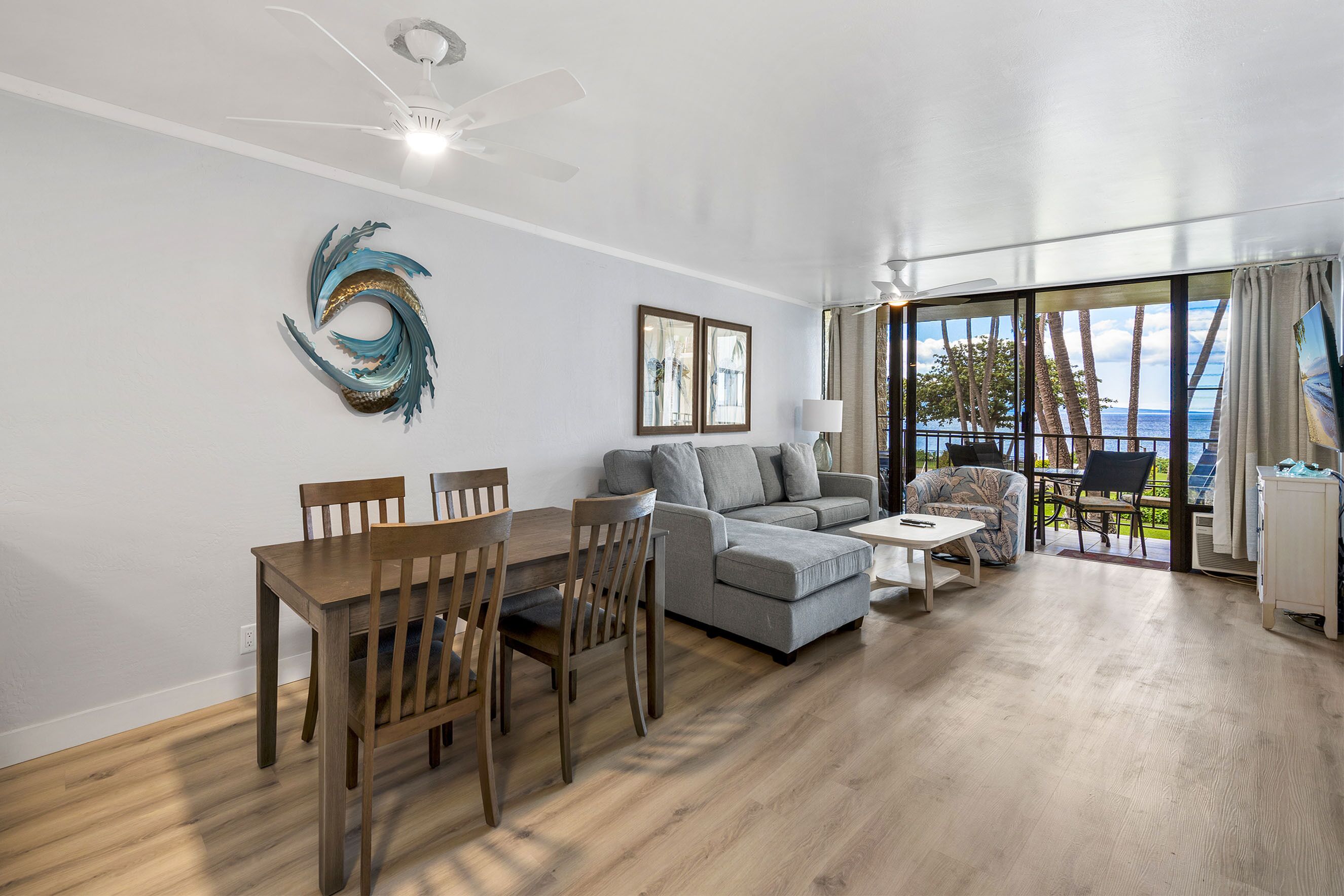 Een moderne woonkamer met een eethoek, een grijze bank en uitzicht op de oceaan.