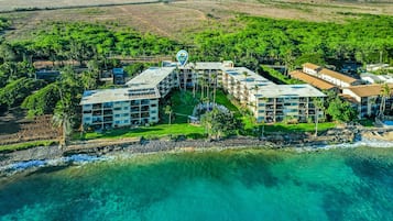 Vue aérienne d’un complexe hôtelier comprenant plusieurs bâtiments, une plage et une végétation luxuriante.
