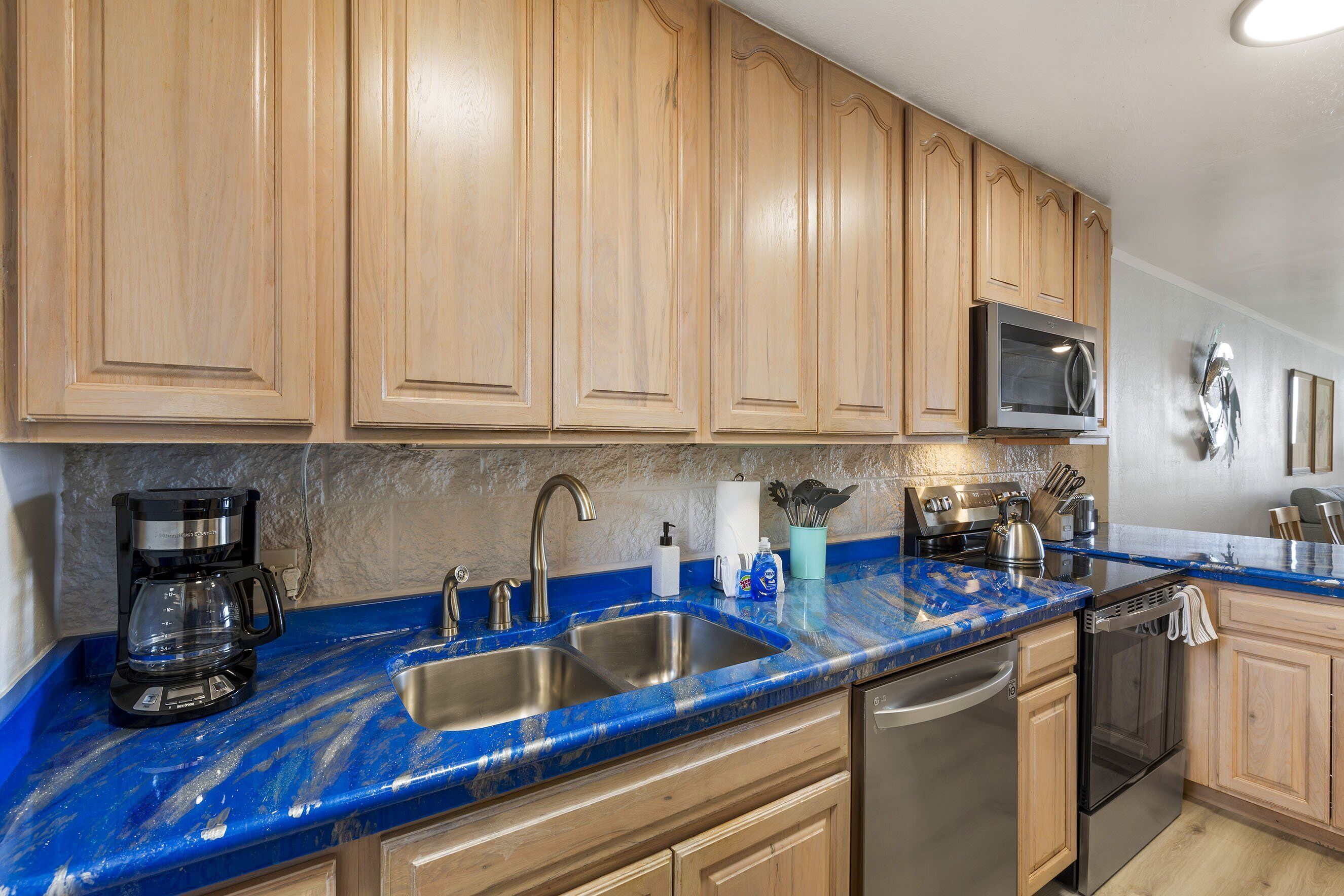 A kitchen with wooden cabinets, a stainless steel sink, a microwave, and a dishwasher.