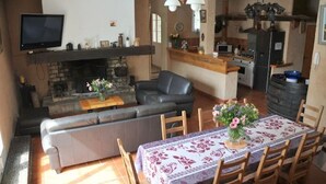 A living room with a fireplace, sofa, and dining table. - Gîte 8 pers air-conditioned, 3 bedrooms with bathrooms, private pool. Peaceful (Évenos)