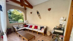 A sunlit patio with a wooden sofa, a coffee table, and a large vase. - Gîte 8 pers air-conditioned, 3 bedrooms with bathrooms, private pool. Peaceful (Évenos)