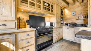 A kitchen with wooden cabinets, a stove, a microwave, and a clock on the wall.