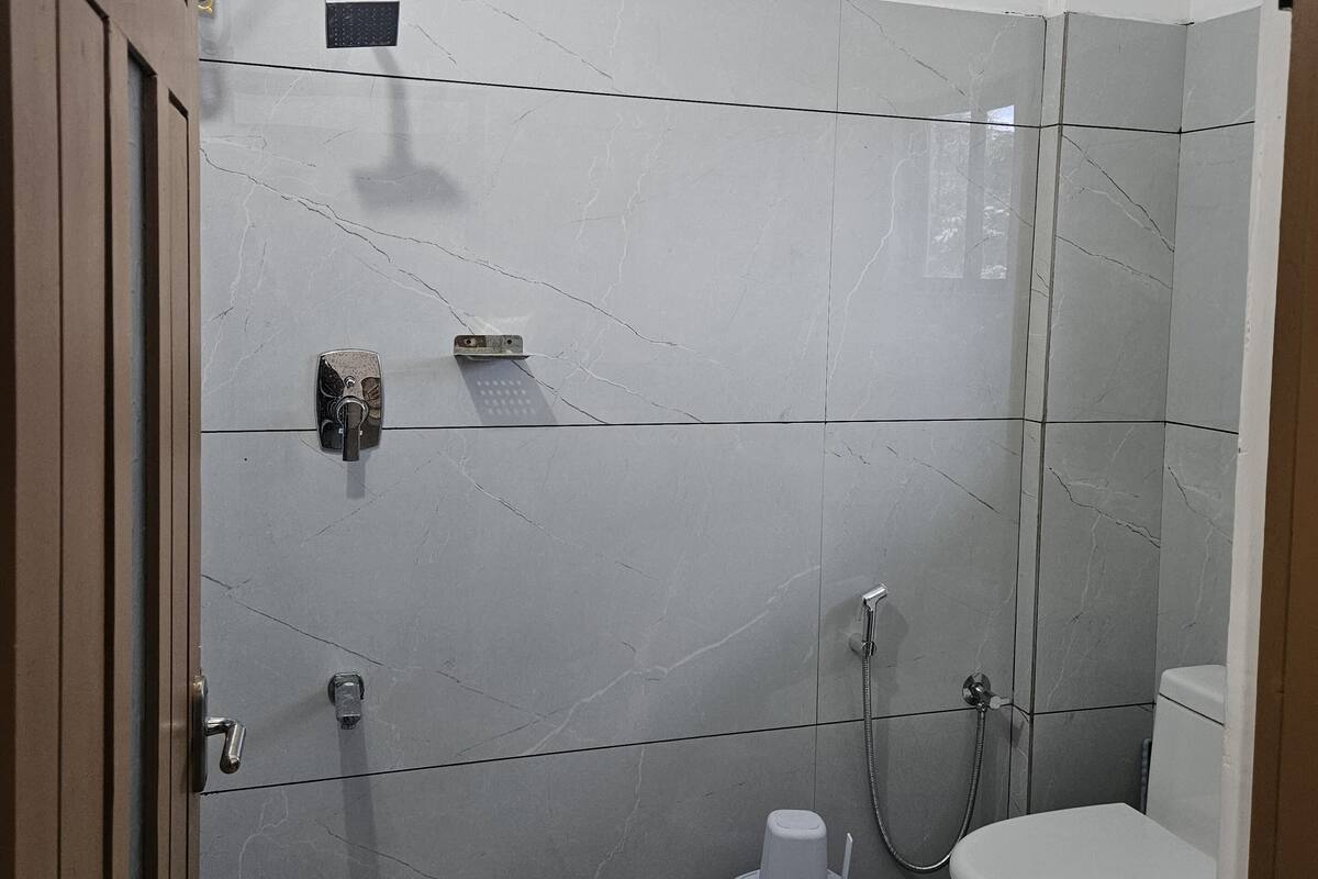 Een kleine, moderne badkamer met toilet, douche en wastafel.