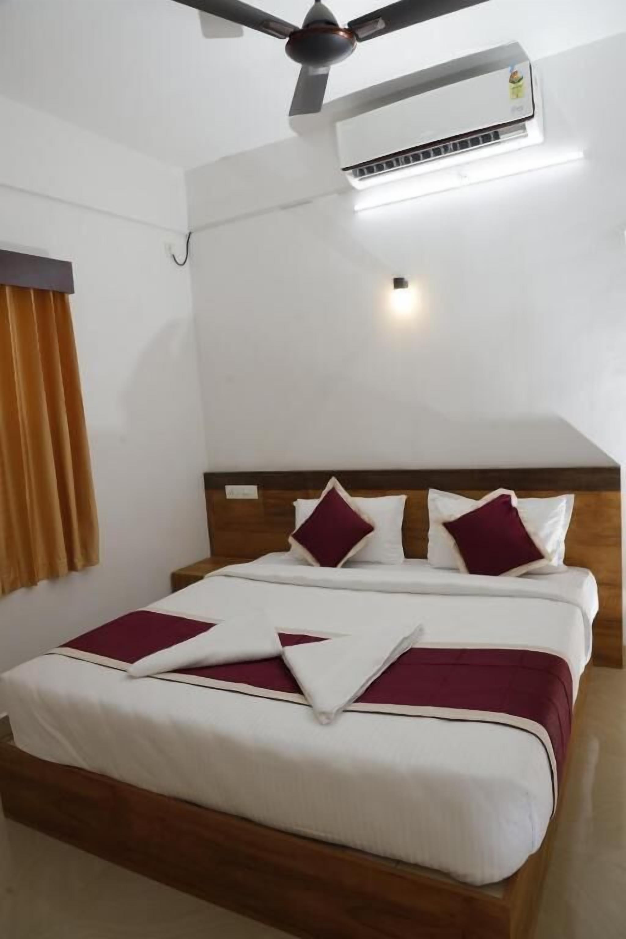Un lit bien fait, avec une tête de lit en bois, un ventilateur de plafond et un appareil de climatisation placé au-dessus.