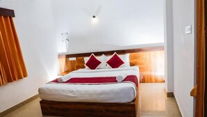 Un lit bien fait, avec une tête de lit en bois, une literie blanche et des oreillers rouges.