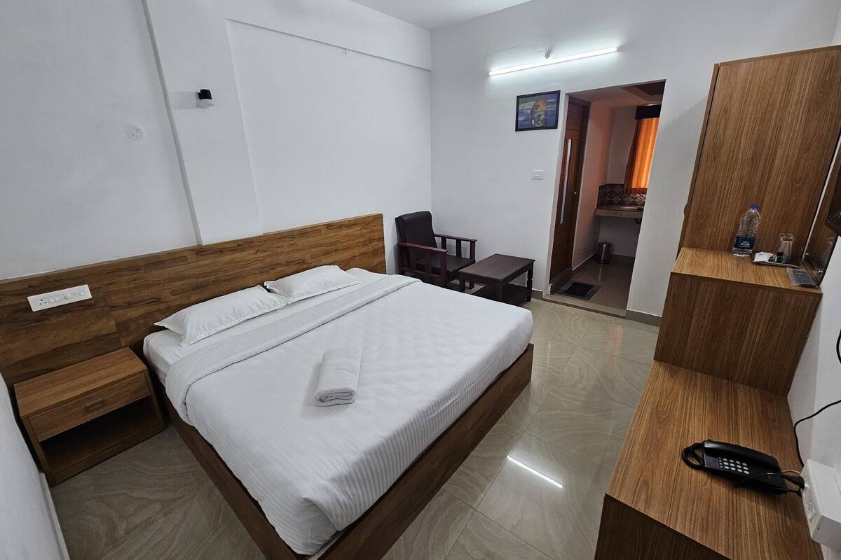 Een hotelkamer met een houten bed, een bureau, een stoel, een spiegel en een plafondventilator.