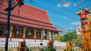 A traditional building with a red roof and ornate decorations, surrounded by a white fence and greenery.