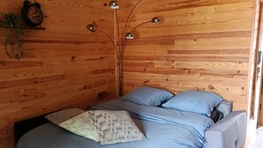 A wooden cabin bedroom with a bed, bedside lamps, and a clock on the wall.