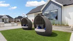 A modern house with two outdoor egg-shaped seating areas on a well-maintained lawn. - Modern Magnolia Cottage | Pool & Gym Access (Magnolia)