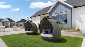 Une maison moderne avec deux chaises suspendues à l’extérieur, installées sur une pelouse bien entretenue.