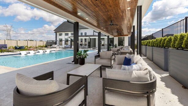 Un espace extérieur abrité avec une piscine, des sièges et une vue sur une maison en arrière-plan.
