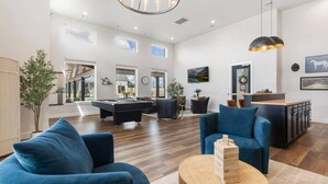 Un vaste espace de vie comprenant une table de billard, des canapés bleus et une table basse en bois.