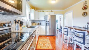 A modern kitchen with stainless steel appliances, white cabinets, and a wooden floor. - Walk to Gold Beach: Charming Cottage w/ Yard! (Gold Beach)