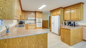 A kitchen with wooden cabinets, a countertop, a sink, a stove, and a refrigerator.