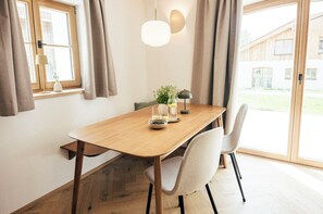 Un coin repas avec une table en bois, deux chaises, un vase de fleurs et une lampe.
