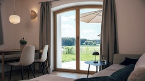 Une chambre moderne équipée d ’un lit, d’un bureau et offrant une vue sur un paysage verdoyant grâce à une porte-fenêtre coulissante.