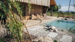Une terrasse en bois avec des chaises longues et une piscine.