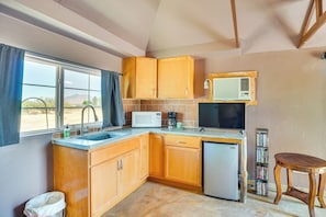 Compact kitchen area with microwave, refrigerator, and sink, offering a view of the outdoors.
