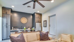 Una cocina moderna con armarios oscuros, una isla central y un comedor con sofá y sillones color beige.