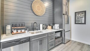 Una cocina moderna con armarios grises, un refrigerador de acero inoxidable, un lavabo y una cafetera.