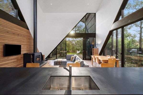 Un interior moderno con cocina, comedor y un amplio ventanal que ofrece vistas al exterior.